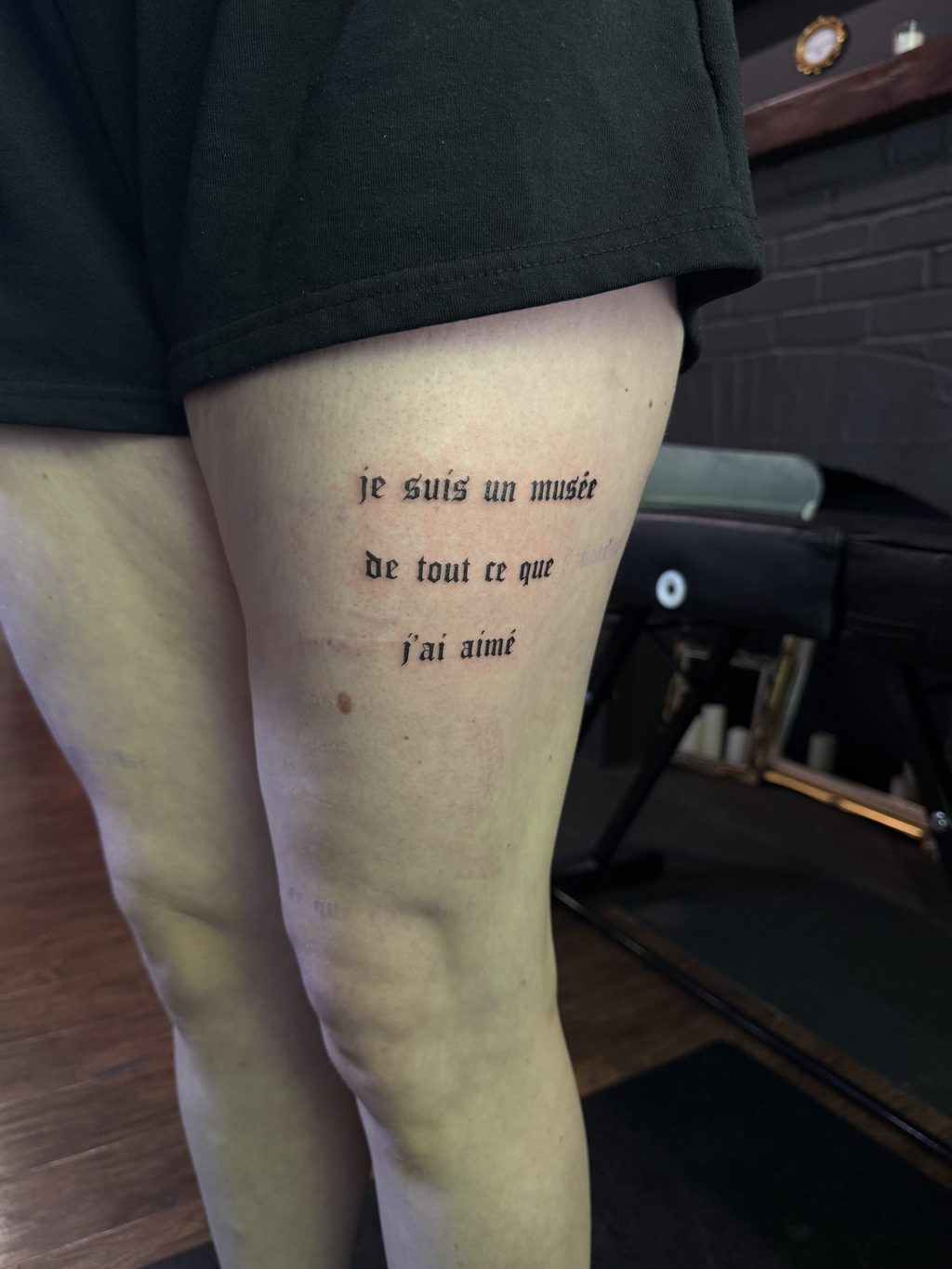 Blackletter script lettering tattoo on the forearm.