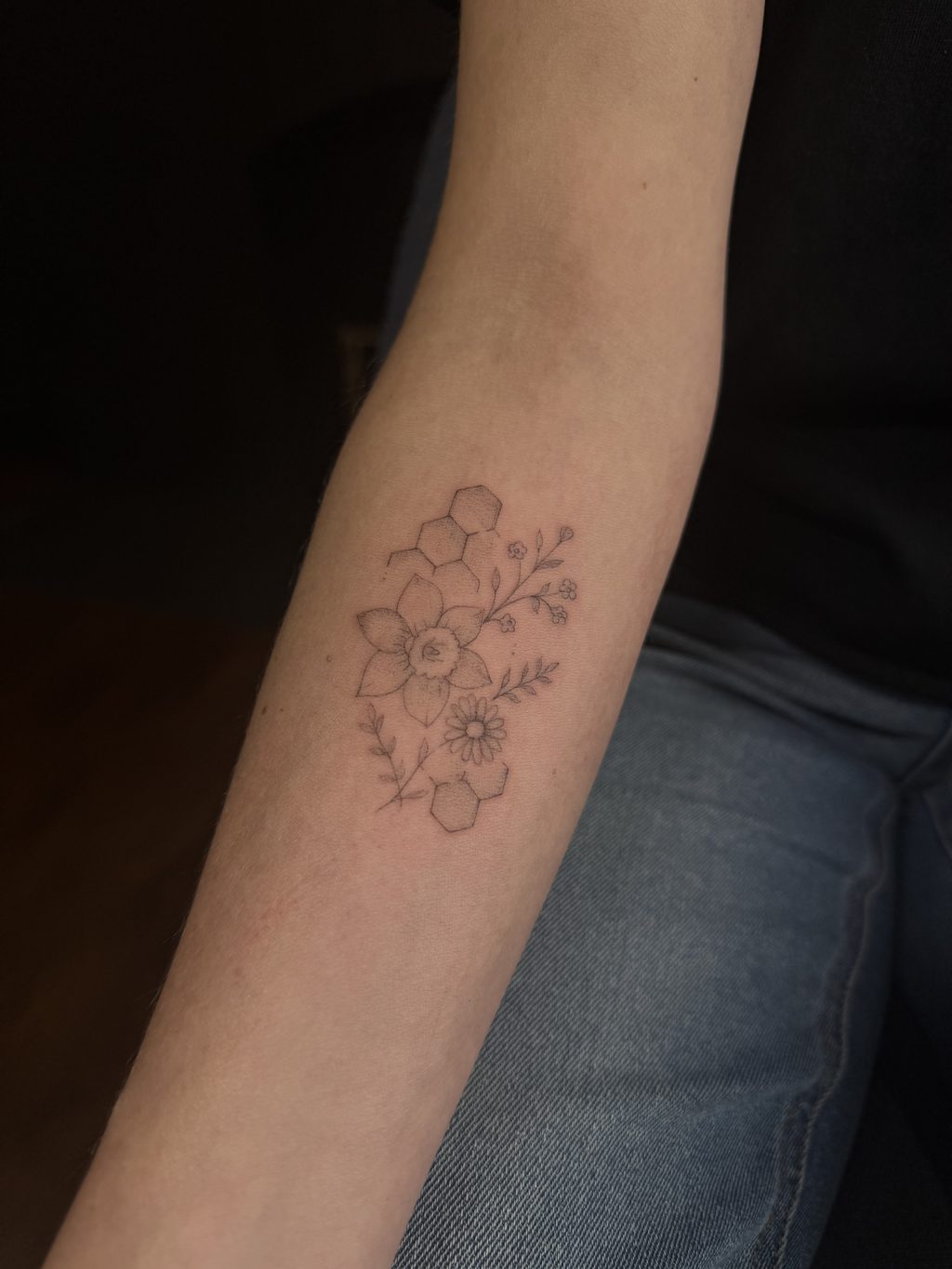 Fine-line wildflowers with a honeycomb cluster on the forearm.
