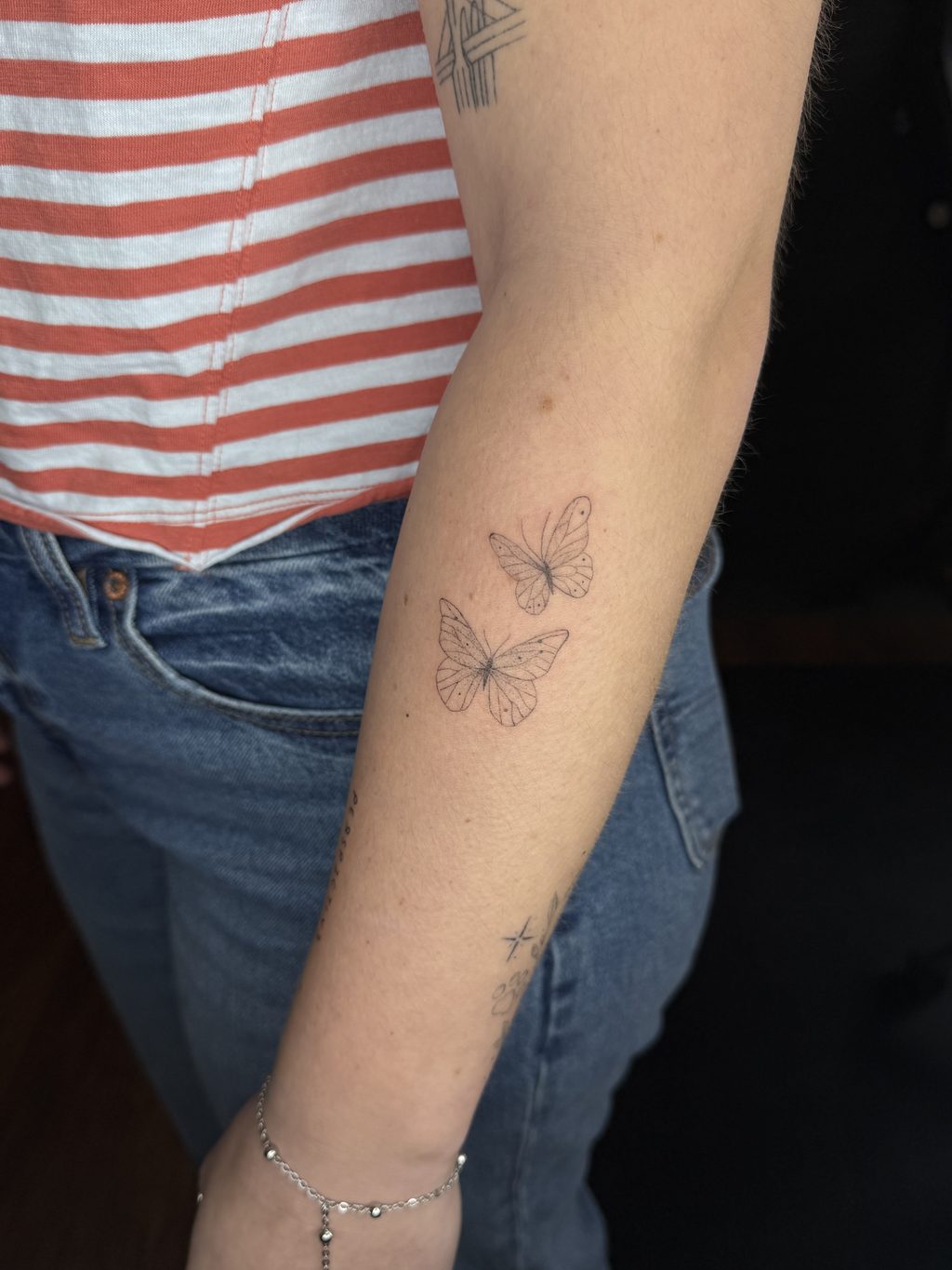 Two fine-line butterflies with small sparkles on the forearm.